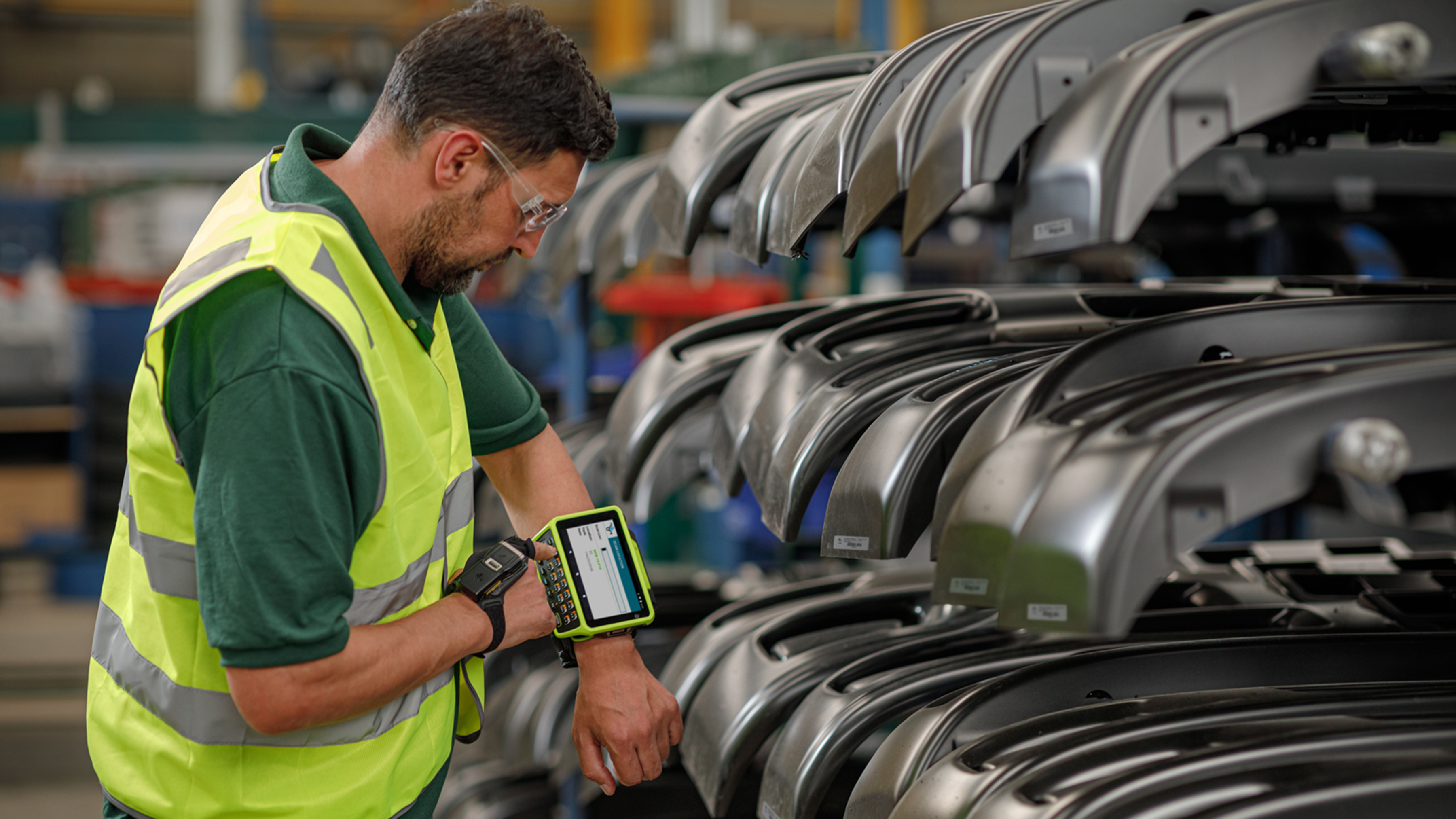Assembly worker using Zebra WT6400 and RS5100 wearable mobile computers to select parts via barcode scanning.