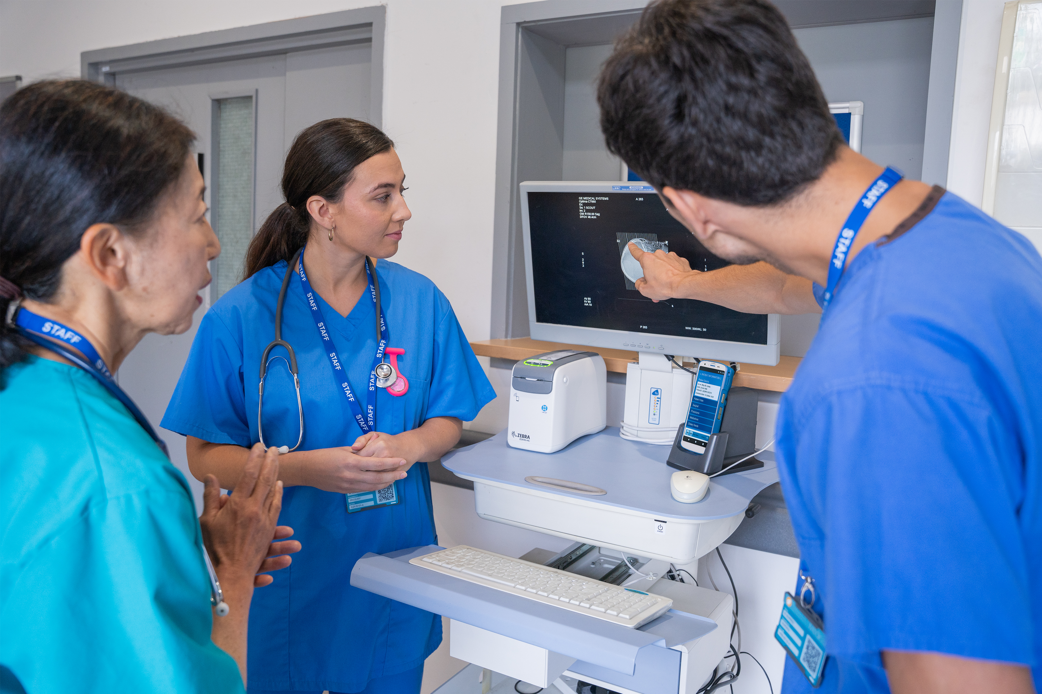 Nurses reviewing patient records on screen together in a hospital.
