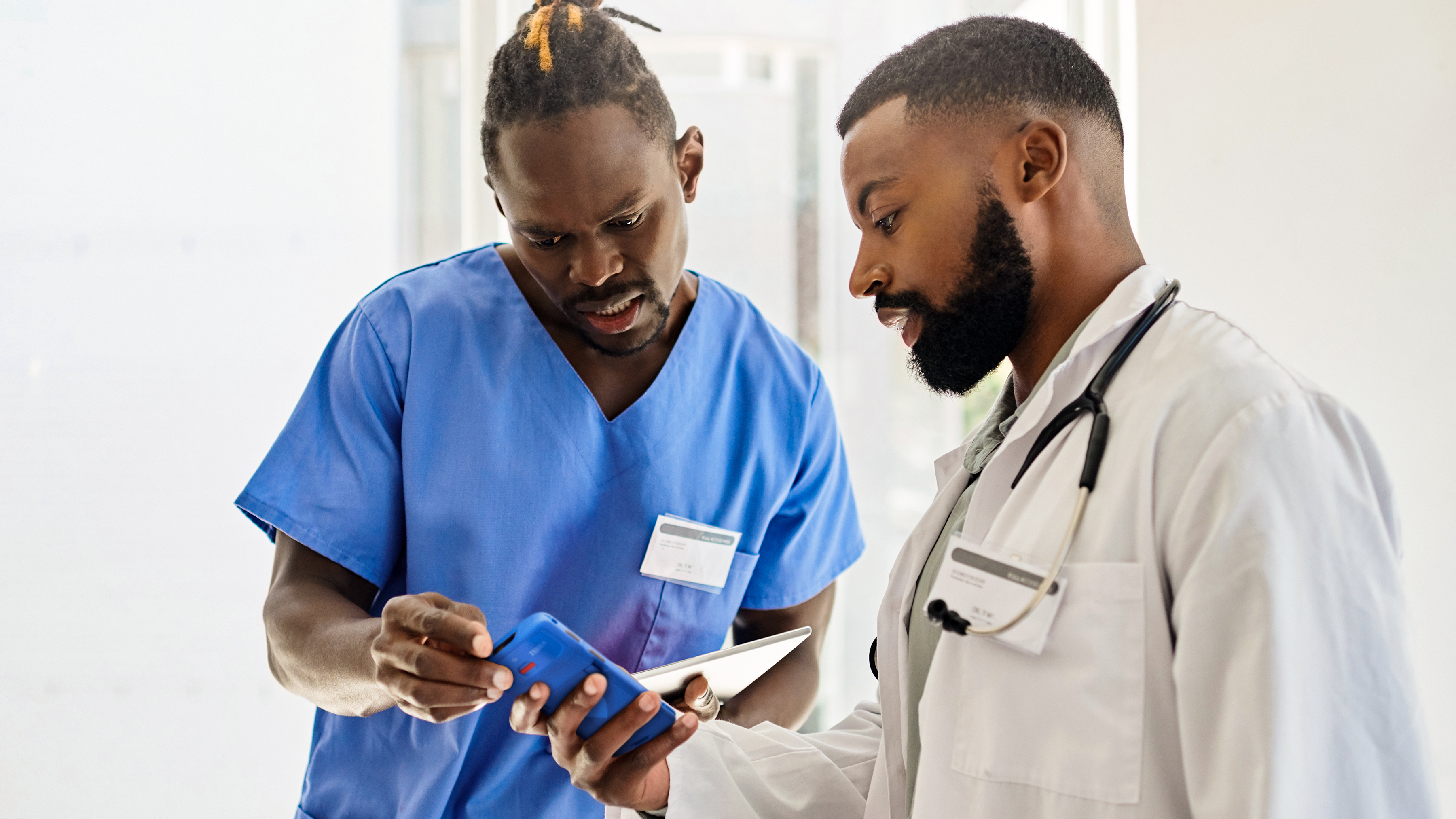 Two healthcare professionals reviewing data on a handheld mobile computer.