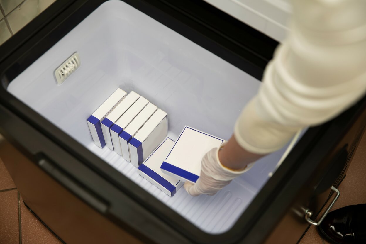 Pharmacist packing temperature-dependent medication into a cooler.