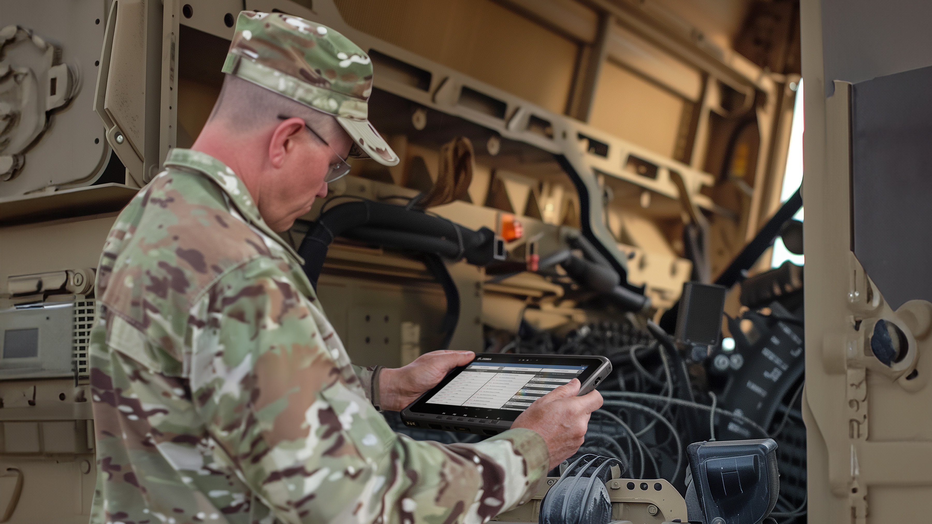 American soldier using an ET6x rugged tablet to inspect a military vehicle.