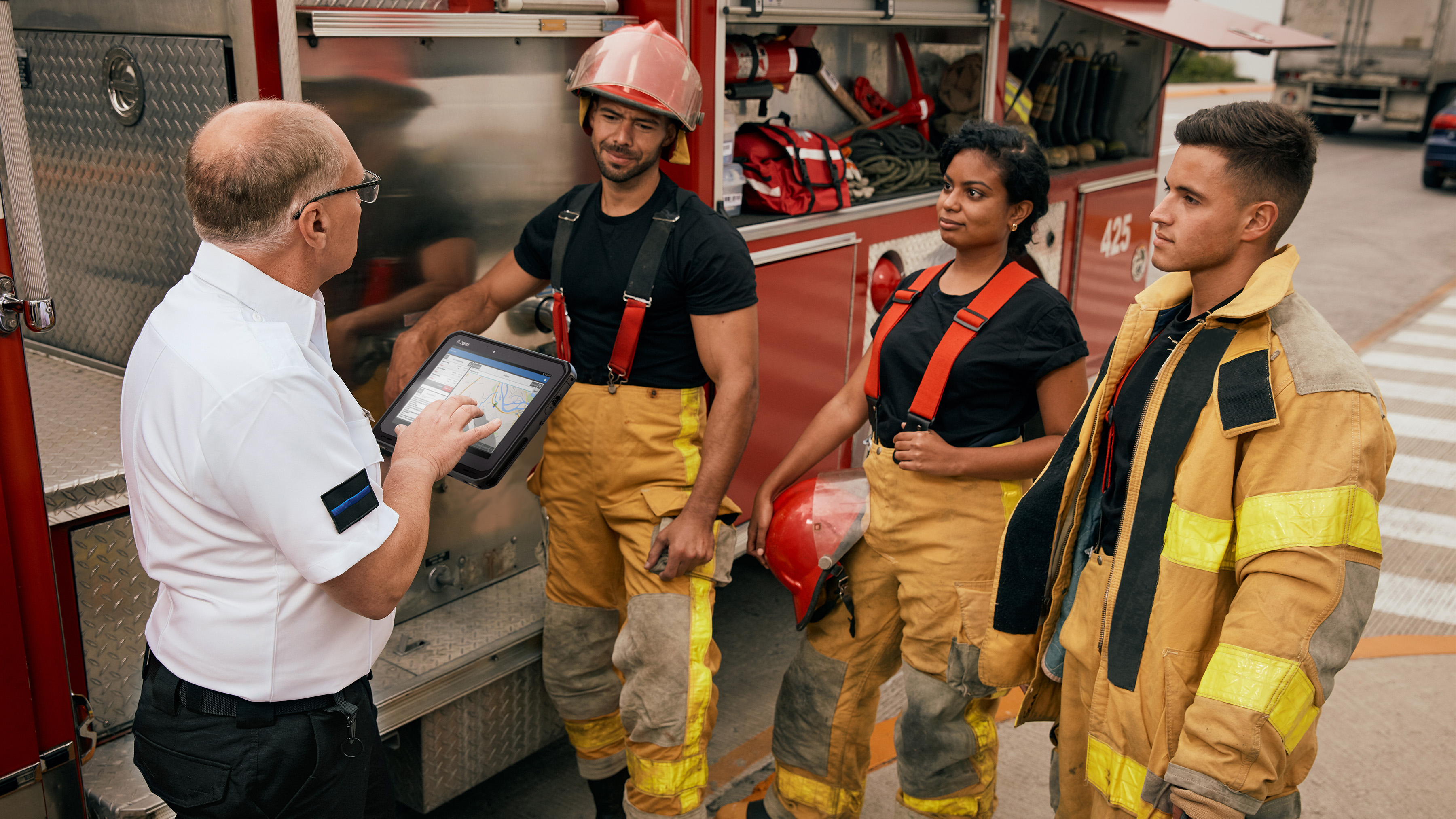 Firefighter team having a meeting next to the fire truck, using a ET6x Series rugged tablet.