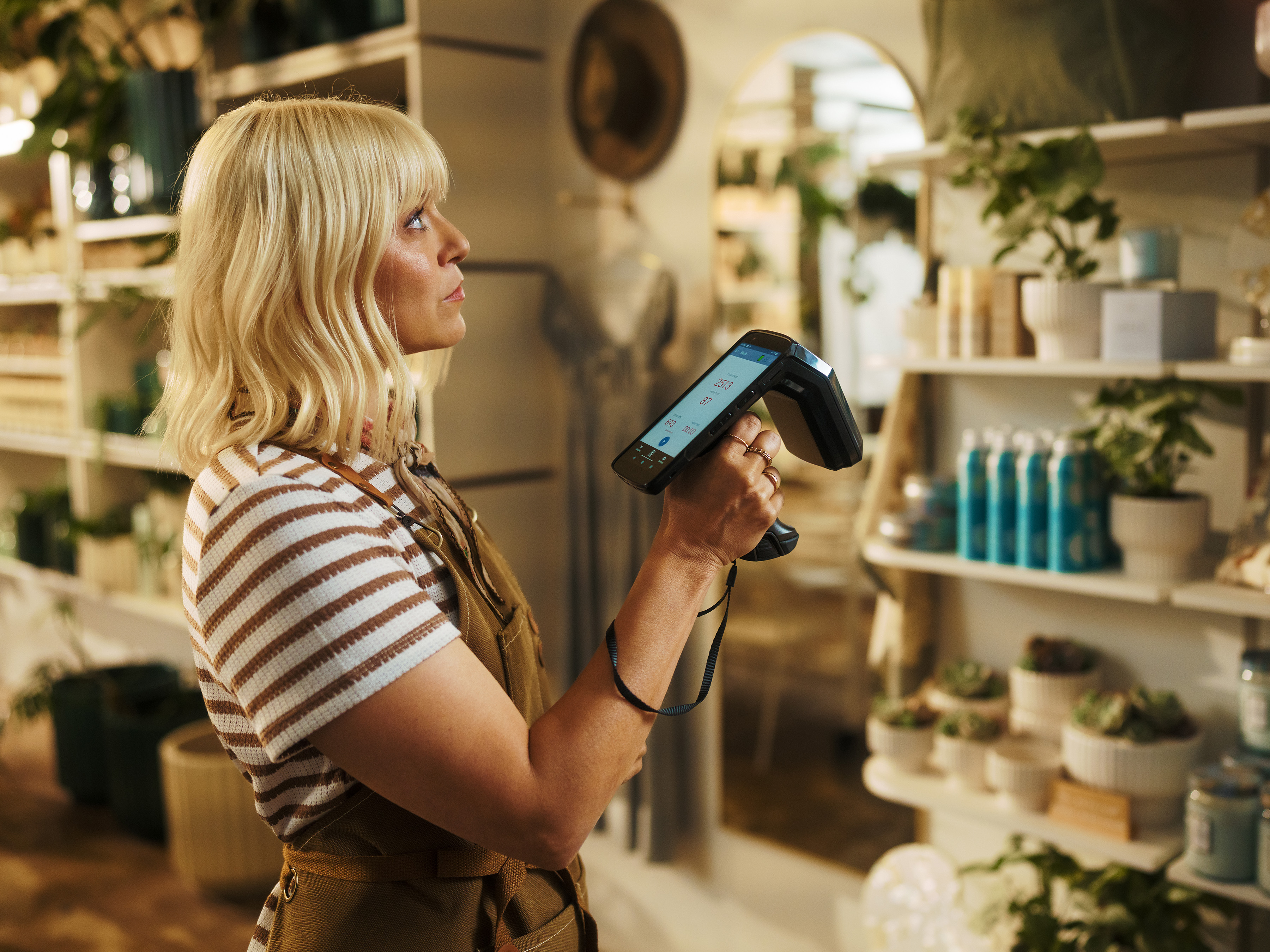 Retail associate holds a Zebra TC22R RFID reader while working on the sales floor of a boutique retail store.