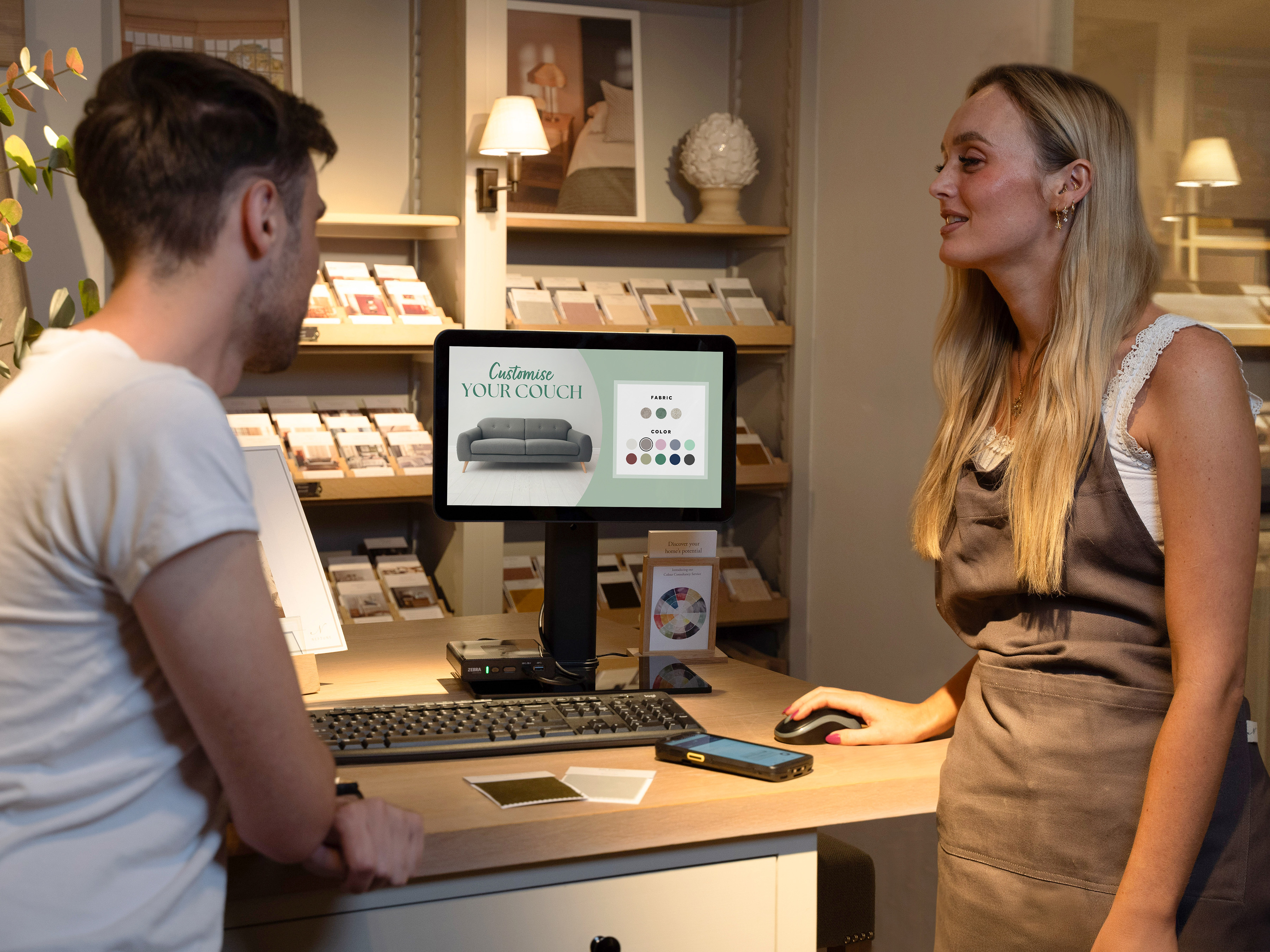 A retail associate using ZEC500 as a workstation with TD50 to assist a customer, TC53 is in the background