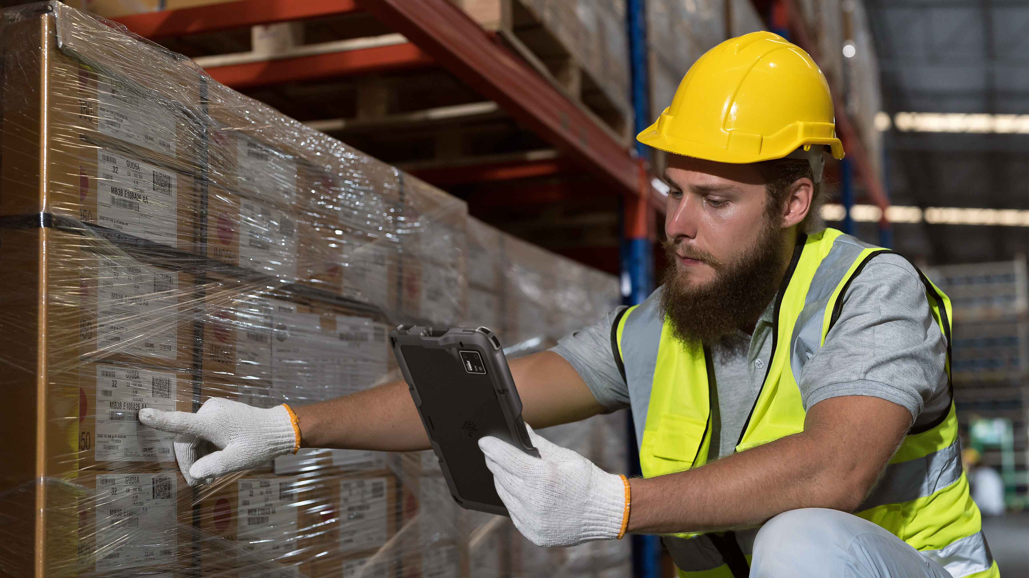 Man in a warehouse with ET401 tablet scanning a barcode label on a box.