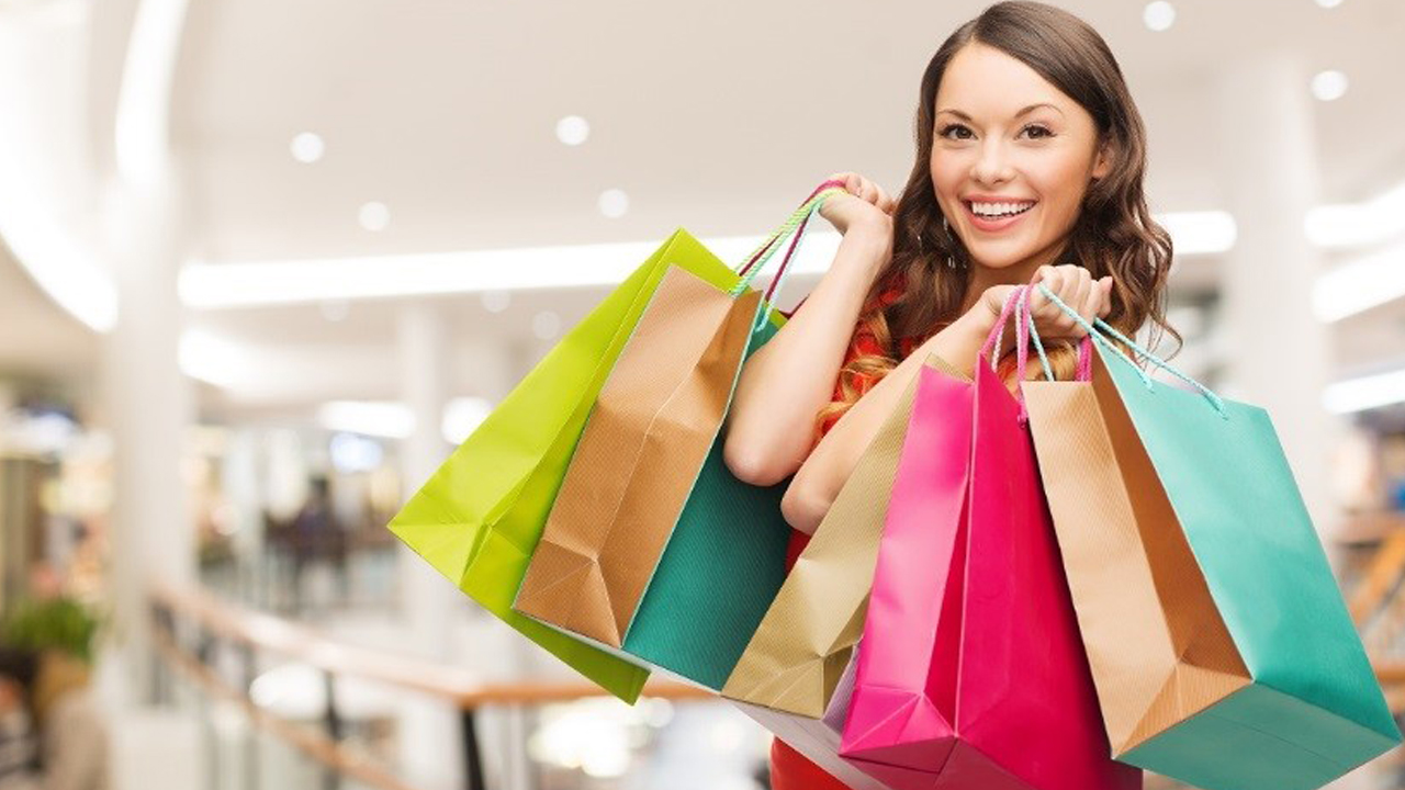 A young lady walks out of a store with several shopping bags in hand.