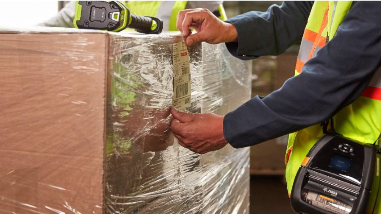 A warehouse worker applies a label to a box