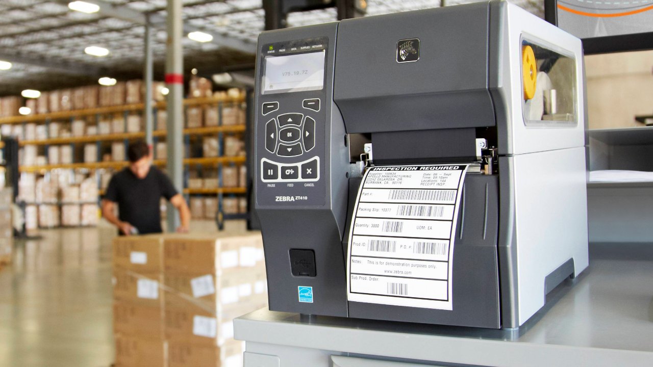 A Zebra ZT400-series industrial thermal transfer printer printing a label in a warehouse