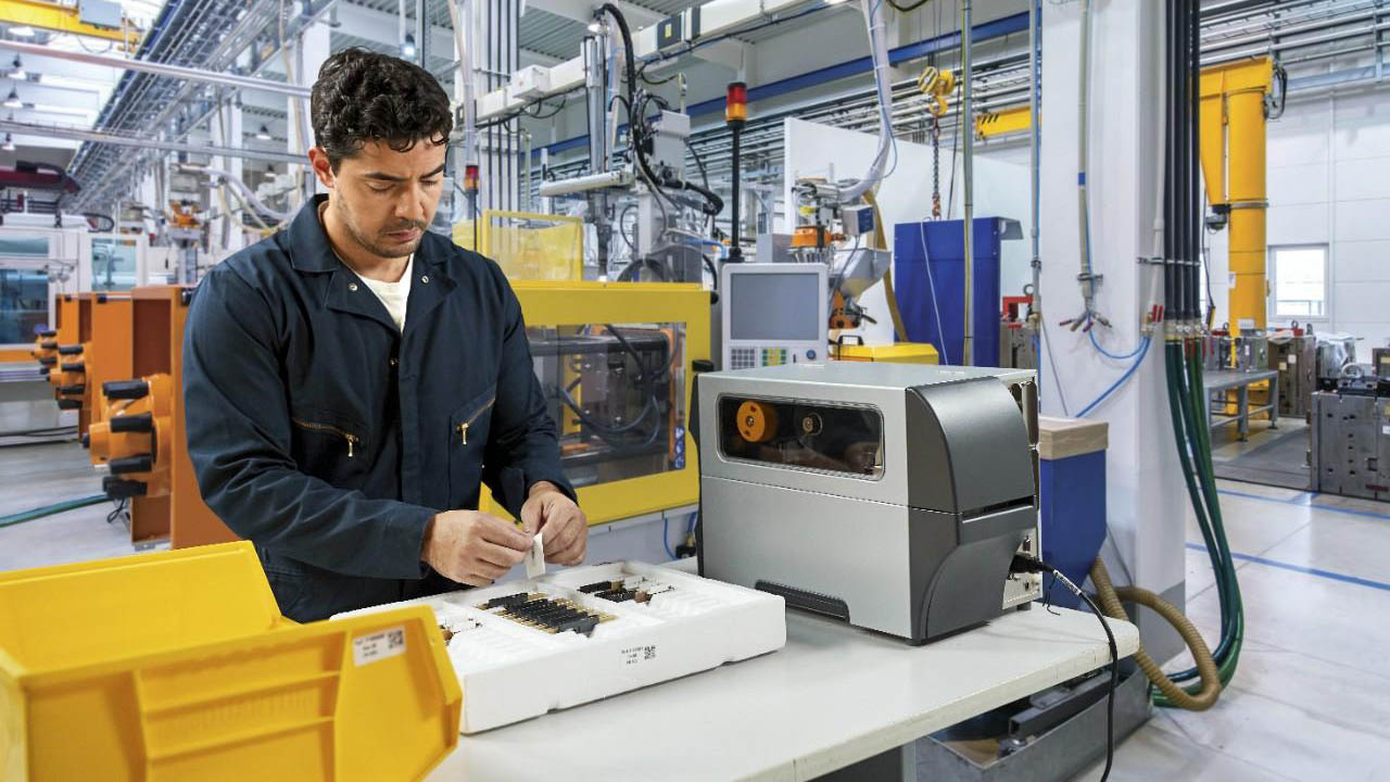 A manufacturing worker applies a label to a component