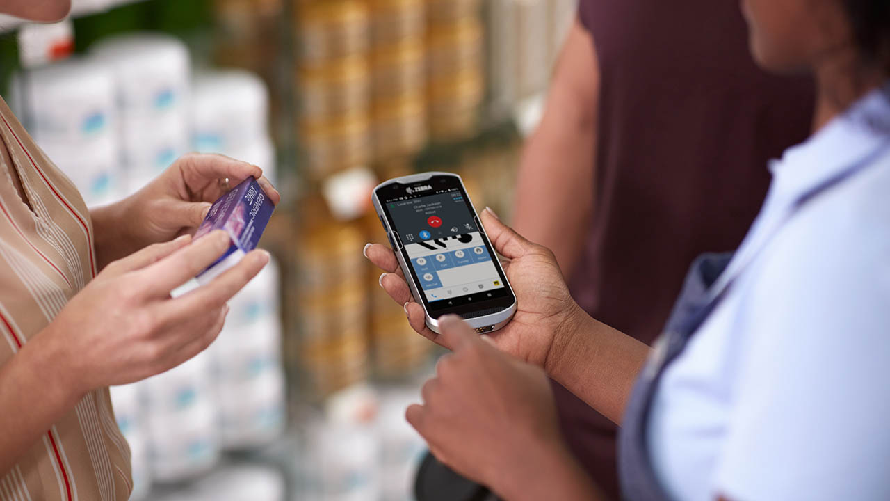 A retail associate looks at her mobile computer while helping a customer.