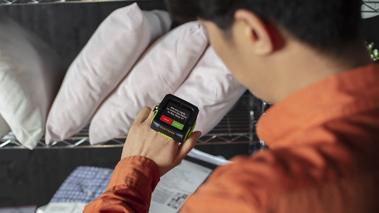 A retail store associate looks at his Zebra WS50 wearable Android mobile computer for task guidance 