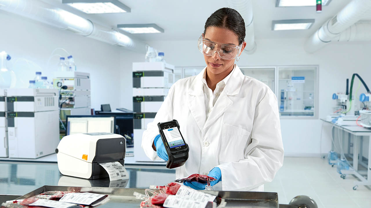 A lab technician uses a Zebra RFD40 RFID sled to read a tag on a blood bag