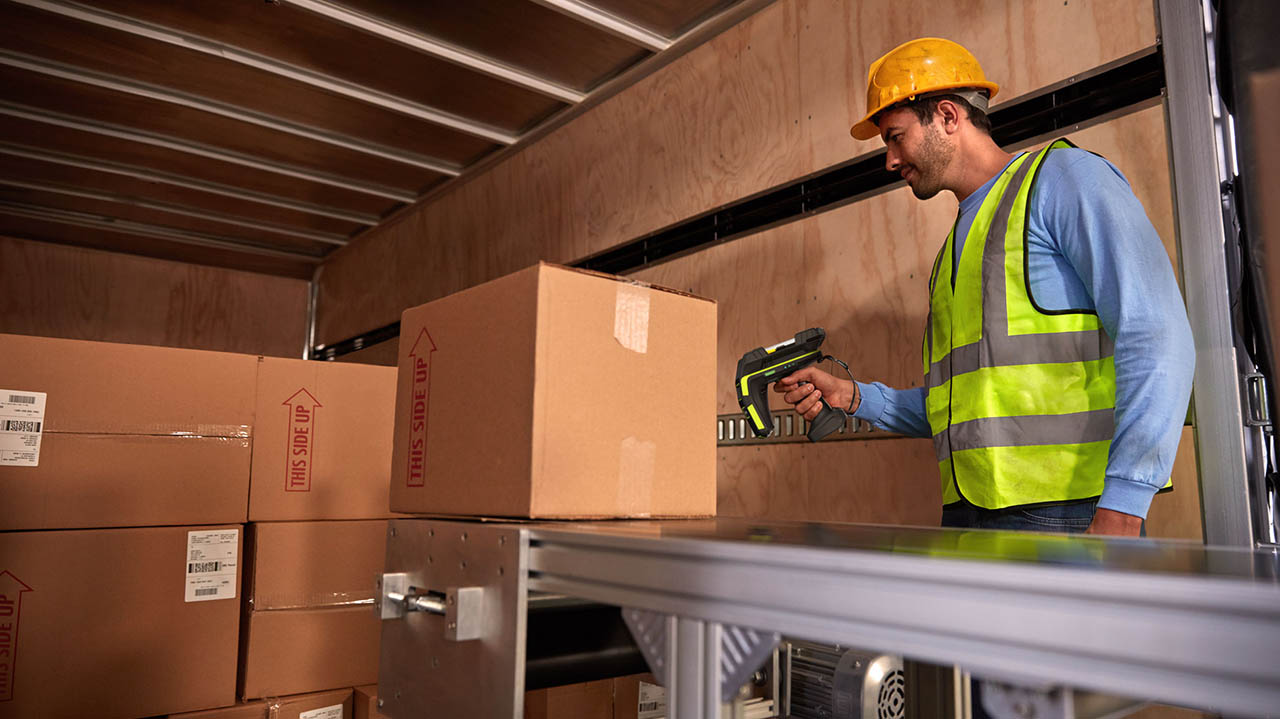 A warehouse worker uses a Zebra RFD90 RFID sled to process inbound inventory