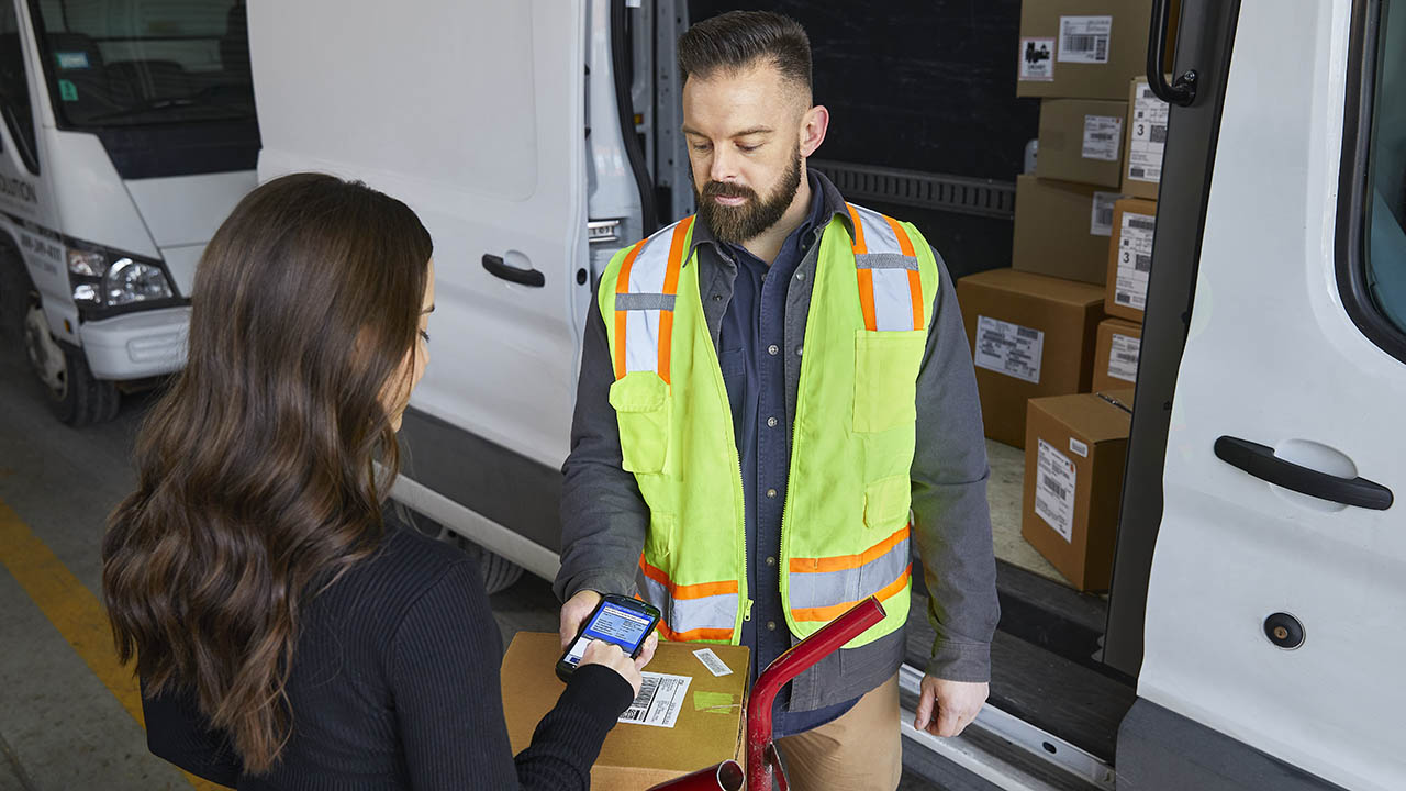 A delivery driver asks a customer to sign for a delivery on his Zebra TC58 mobile computer